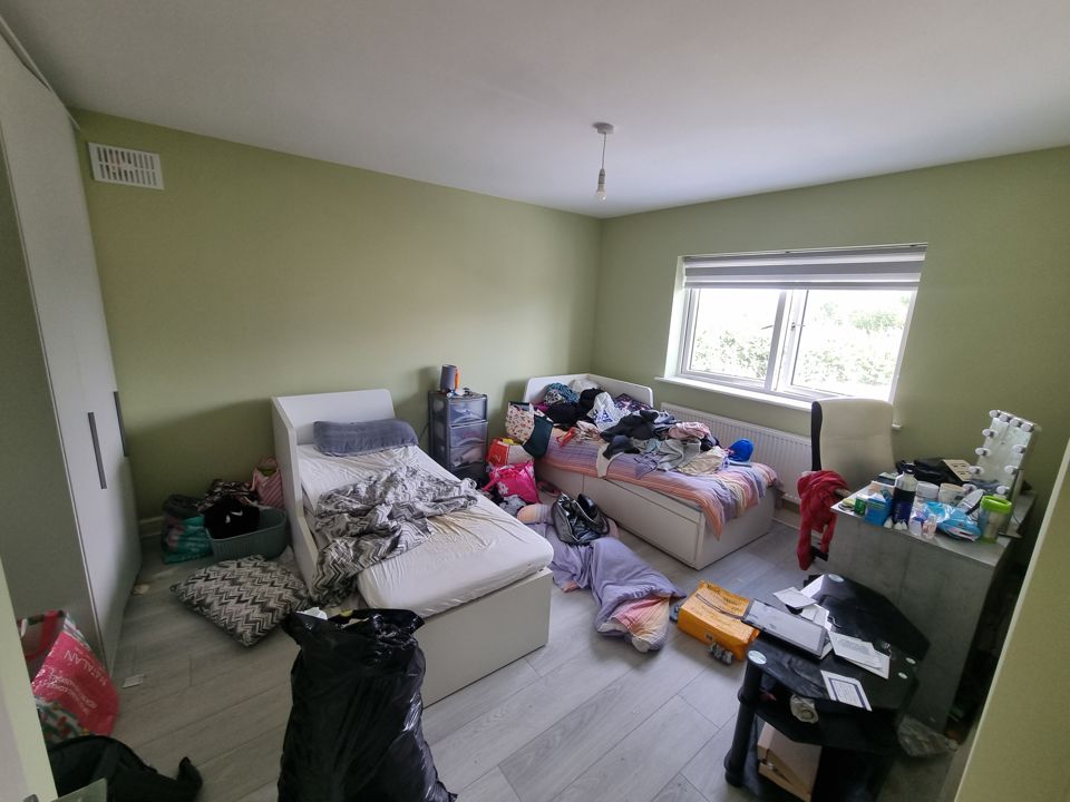 Bedroom with clothes and belongings over the beds before clearance