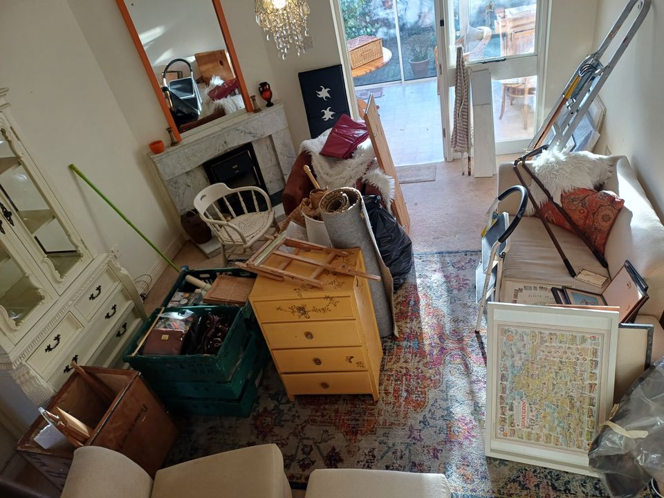 Living room with furniture, boxes and framed pictures set out before a bereavement clearance